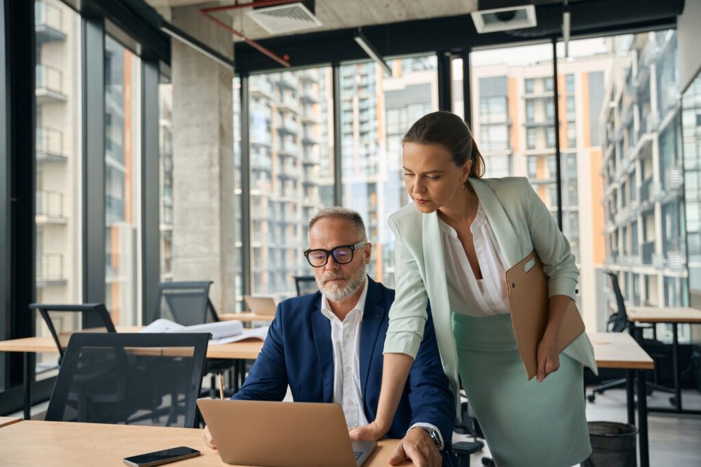 Focused office colleagues working on laptop with serious faces